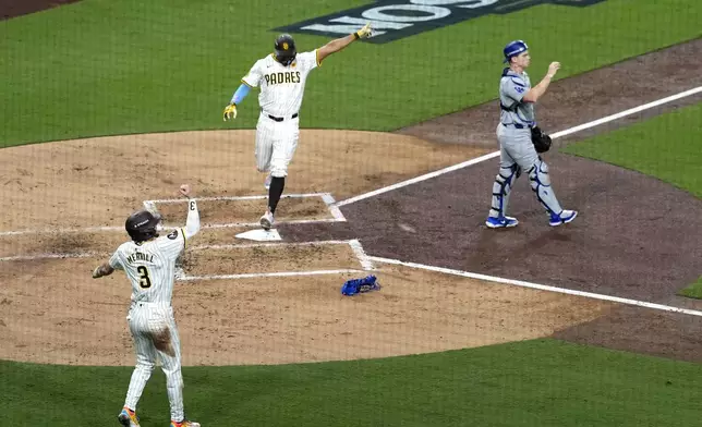 San Diego Padres' Xander Bogaerts, center, scores past Los Angeles Dodgers catcher Will Smith, right, as Jackson Merrill celebrates on a double by David Peralta during the second inning in Game 3 of a baseball NL Division Series Tuesday, Oct. 8, 2024, in San Diego. (AP Photo/Ashley Landis)