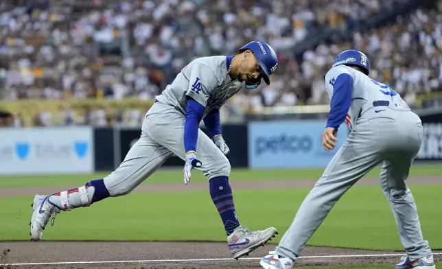 Los Angeles Dodgers' Mookie Betts celebrates with third base coach Dino Ebel after Betts' solo home run during the first inning in Game 3 of a baseball NL Division Series against the San Diego Padres, Tuesday, Oct. 8, 2024, in San Diego. (AP Photo/Gregory Bull)