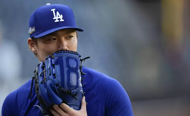 Los Angeles Dodgers pitcher Yoshinobu Yamamoto holds a glove up to his face during batting practice before Game 3 of a baseball NL Division Series against the San Diego Padres, Tuesday, Oct. 8, 2024, in San Diego. (AP Photo/Gregory Bull)