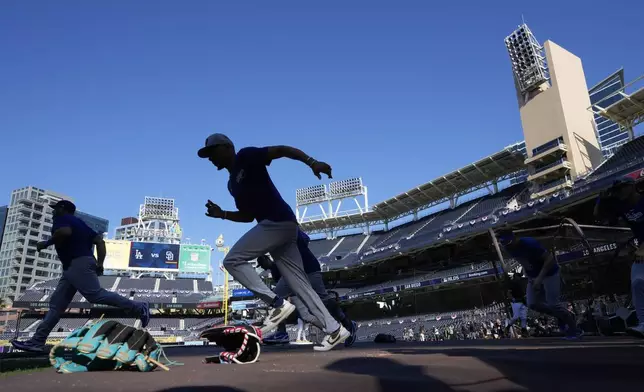 Los Angeles Dodgers' Mookie Betts warms up before Game 3 of a baseball NL Division Series against the San Diego Padres, Tuesday, Oct. 8, 2024, in San Diego. (AP Photo/Gregory Bull)