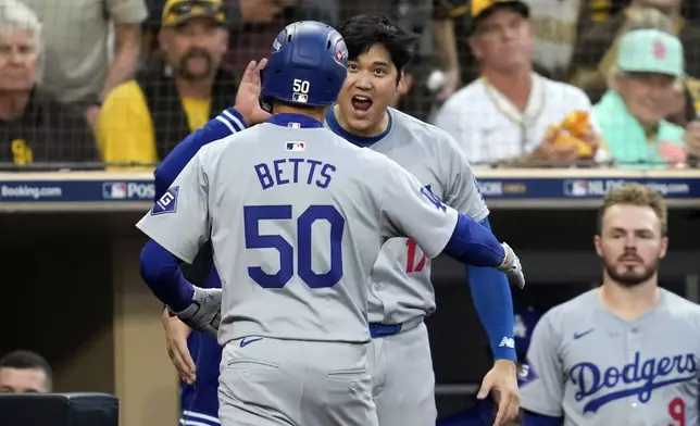 Los Angeles Dodgers' Mookie Betts (50) celebrates his solo home run with Shohei Ohtani during the first inning in Game 3 of a baseball NL Division Series against the San Diego Padres, Tuesday, Oct. 8, 2024, in San Diego. (AP Photo/Ashley Landis)