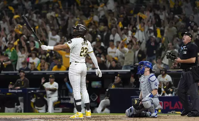 San Diego Padres' Fernando Tatis Jr., left, follows through on his two-run home run as Los Angeles Dodgers catcher Will Smith, center, and home plate umpire Cory Blaser watch during the second inning in Game 3 of a baseball NL Division Series, Tuesday, Oct. 8, 2024, in San Diego. (AP Photo/Gregory Bull)