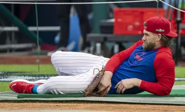 Philadelphia Phillies' Bryce Harper lays on the field during a baseball workout, Friday, Oct. 4, 2024, in Philadelphia, ahead of the National League Division Series against the New York Mets,. (AP Photo/Chris Szagola)