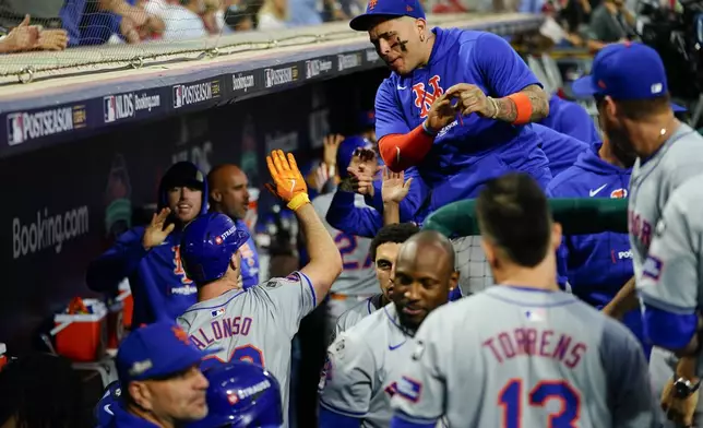 New York Mets' Pete Alonso, lower left, high fives a teammate after hitting an RBI sacrifice fly during the eighth inning of Game 1 of a baseball NL Division Series against the Philadelphia Phillies, Saturday, Oct. 5, 2024, in Philadelphia. (AP Photo/Chris Szagola)