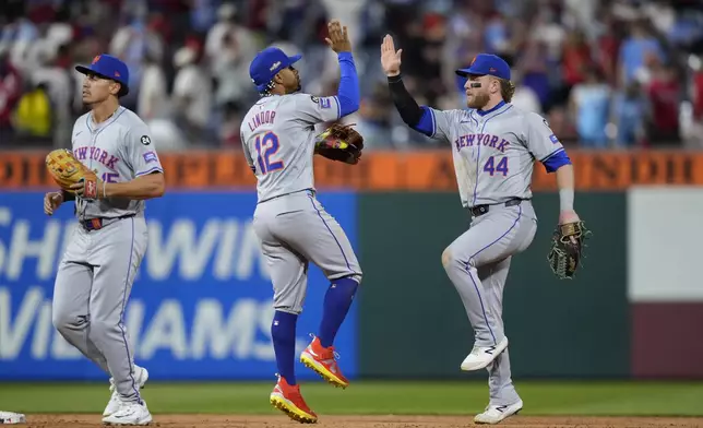 New York Mets' Harrison Bader (44), Francisco Lindor (12), and Tyrone Taylor celebrate after winning Game 1 of a baseball NL Division Series against the Philadelphia Phillies, Saturday, Oct. 5, 2024, in Philadelphia. (AP Photo/Matt Slocum)