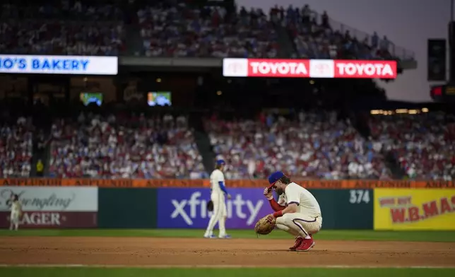 Philadelphia Phillies first base Bryce Harper rests during a pitching change during the eighth inning of Game 1 of a baseball NL Division Series against the New York Mets, Saturday, Oct. 5, 2024, in Philadelphia. (AP Photo/Matt Slocum)