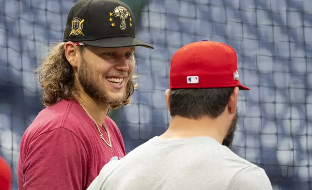 Philadelphia Phillies' Alec Bohm, left, talks with Kyle Schwarber, right, during a baseball workout, Friday, Oct. 4, 2024, in Philadelphia, ahead of the National League Division Series against the New York Mets. (AP Photo/Chris Szagola)