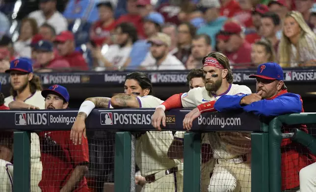 Philadelphia Phillies' Bryce Harper, second right, looks on from the dugout with teammates during the ninth inning of Game 1 of a baseball NL Division Series against the New York Mets, Saturday, Oct. 5, 2024, in Philadelphia. (AP Photo/Chris Szagola)