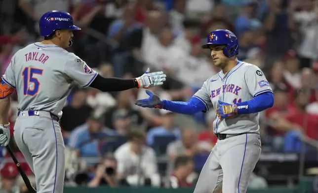 New York Mets' Jose Iglesias, right, and Tyrone Taylor celebrate after Iglesias scored on a sacrifice fly by Starling Marte during the eighth inning of Game 1 of a baseball NL Division Series, Saturday, Oct. 5, 2024, in Philadelphia. (AP Photo/Matt Slocum)