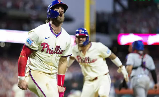 Philadelphia Phillies' Bryce Harper, left, and Nick Castellanos celebrate after scoringon a two-run triple hit by Bryson Stott during the eighth inning of Game 2 of a baseball NL Division Series against the New York Mets, Sunday, Oct. 6, 2024, in Philadelphia. (AP Photo/Matt Slocum)