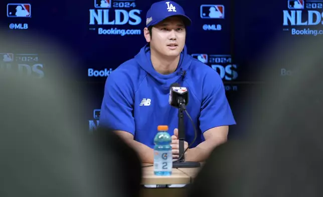 Los Angeles Dodgers' Shohei Ohtani fields questions ahead of Game 5 of a baseball National League Division Series against the San Diego Padres, Thursday, Oct. 10, 2024, in Los Angeles. (AP Photo/Ashley Landis)