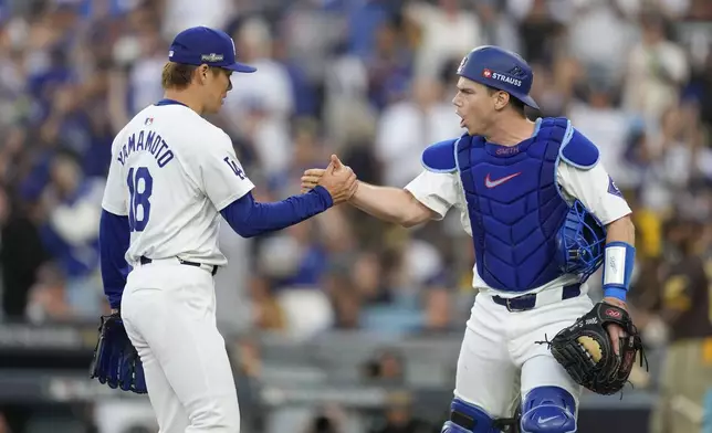 Los Angeles Dodgers starting pitcher Yoshinobu Yamamoto, left, shakes hands with catcher Will Smith after San Diego Padres' Fernando Tatis Jr. grounded into a double play during the third inning in Game 5 of a baseball NL Division Series Friday, Oct. 11, 2024, in Los Angeles. (AP Photo/Ashley Landis)