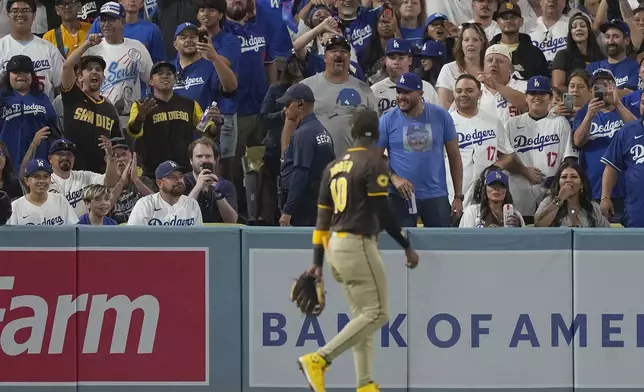 Fans react toward San Diego Padres left fielder Jurickson Profar, foreground, after items were thrown at him in the outfield during the seventh inning in Game 2 of a baseball NL Division Series between the Los Angeles Dodgers and the Padres, Sunday, Oct. 6, 2024, in Los Angeles. (AP Photo/Mark J. Terrill)