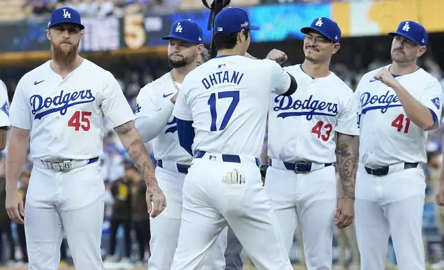 Los Angeles Dodgers' Shohei Ohtani (17) bumps fists with teammates before Game 1 of baseball's NL Division Series against the San Diego Padres, Saturday, Oct. 5, 2024, in Los Angeles. (AP Photo/Ashley Landis)