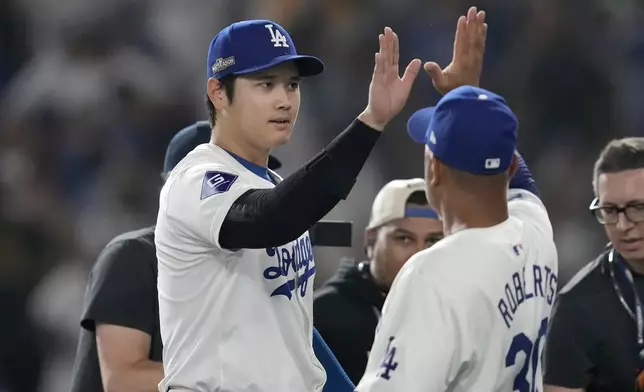 Los Angeles Dodgers' Shohei Ohtani, left, celebrates with manager Dave Roberts after the Dodgers defeated the San Diego Padres in Game 1 of baseball's NL Division Series, Saturday, Oct. 5, 2024, in Los Angeles. (AP Photo/Ashley Landis)