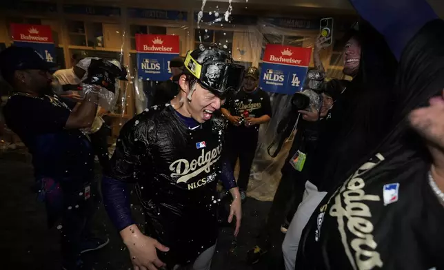 Los Angeles Dodgers pitcher Yoshinobu Yamamoto, center, celebrates in the dugout after a win over the San Diego Padres in Game 5 of a baseball NL Division Series Friday, Oct. 11, 2024, in Los Angeles. (AP Photo/Ashley Landis)