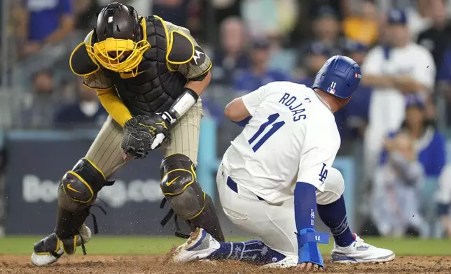 Los Angeles Dodgers' Miguel Rojas (11) is forced out at home plate by San Diego Padres catcher Kyle Higashioka, left, after a ground ball by Freddie Freeman during the fourth inning in Game 1 of baseball's NL Division Series, Saturday, Oct. 5, 2024, in Los Angeles. (AP Photo/Ashley Landis)