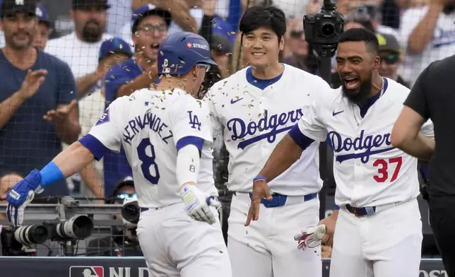 Los Angeles Dodgers' Kiké Hernández (8) celebrates his solo home run with Shohei Ohtani, center, and Teoscar Hernández during the second inning in Game 5 of a baseball NL Division Series against the San Diego Padres, Friday, Oct. 11, 2024, in Los Angeles. (AP Photo/Mark J. Terrill)