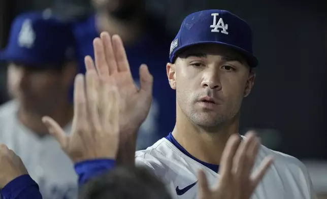 Los Angeles Dodgers starting pitcher Jack Flaherty is high-fived in the dugout after being relieved during the sixth inning in Game 2 of a baseball NL Division Series against the San Diego Padres, Sunday, Oct. 6, 2024, in Los Angeles. (AP Photo/Ashley Landis)