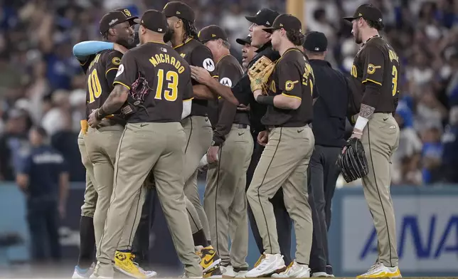 San Diego Padres left fielder Jurickson Profar, left, is held back by teammates after he protested with umpires when items were thrown at him in the outfield during the seventh inning in Game 2 of a baseball NL Division Series against the Los Angeles Dodgers, Sunday, Oct. 6, 2024, in Los Angeles. (AP Photo/Mark J. Terrill)