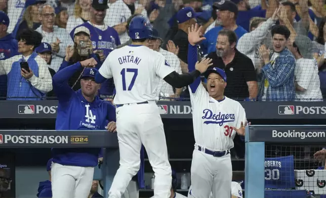 Los Angeles Dodgers' Shohei Ohtani (17) celebrates with manager Dave Roberts, middle right, after Ohtani scored on a single by Teoscar Hernández during the fourth inning in Game 1 of baseball's NL Division Series against the San Diego Padres, Saturday, Oct. 5, 2024, in Los Angeles. (AP Photo/Mark J. Terrill)