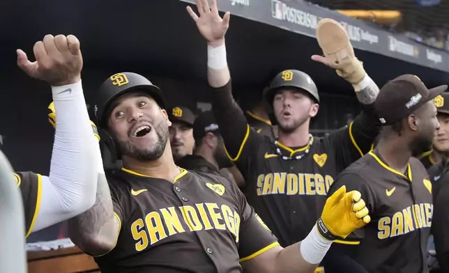 San Diego Padres' David Peralta, left, celebrates in the dugout after hitting a two-run home run that also scored Jackson Merrill, middle, during the second inning in Game 2 of a baseball NL Division Series against the Los Angeles Dodgers, Sunday, Oct. 6, 2024, in Los Angeles. (AP Photo/Mark J. Terrill)