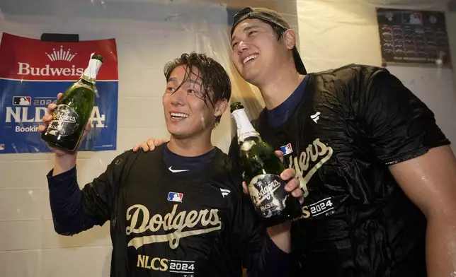 Los Angeles Dodgers' Yoshinobu Yamamoto, left, and Shohei Ohtani celebrate in the clubhouse after a win over the San Diego Padres in Game 5 of a baseball NL Division Series Friday, Oct. 11, 2024, in Los Angeles. (AP Photo/Ashley Landis)