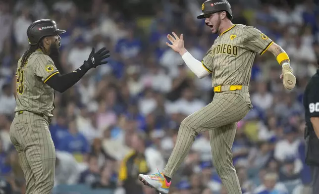 San Diego Padres' Jackson Merrill, right, celebrates with Fernando Tatis Jr. after they both scored on a two-run double hit by Xander Bogaerts during the third inning in Game 1 of baseball's NL Division Series against the Los Angeles Dodgers, Saturday, Oct. 5, 2024, in Los Angeles. (AP Photo/Mark J. Terrill)