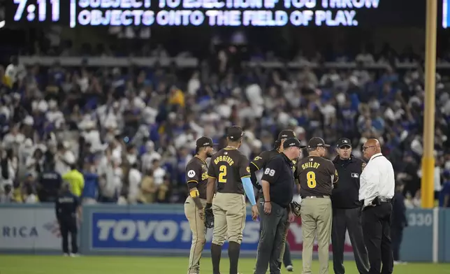 San Diego Padres manager Mike Shildt (8) and players talk to umpires after items were thrown on the field by fans during the seventh inning in Game 2 of a baseball NL Division Series against the Los Angeles Dodgers, Sunday, Oct. 6, 2024, in Los Angeles. (AP Photo/Ashley Landis)