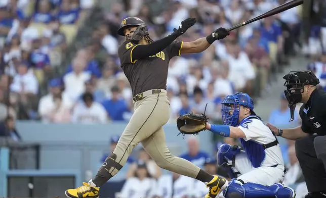 San Diego Padres' Fernando Tatis Jr. watches his double in front of Los Angeles Dodgers catcher Will Smith, bottom, during the third inning in Game 2 of a baseball NL Division Series, Sunday, Oct. 6, 2024, in Los Angeles. (AP Photo/Ashley Landis)