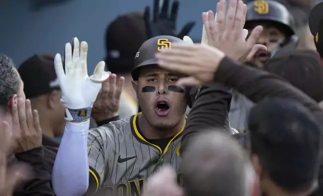 San Diego Padres' Manny Machado, middle, celebrates in the dugout after his two-run home run during the first inning in Game 1 of baseball's NL Division Series against the Los Angeles Dodgers, Saturday, Oct. 5, 2024, in Los Angeles. (AP Photo/Mark J. Terrill)