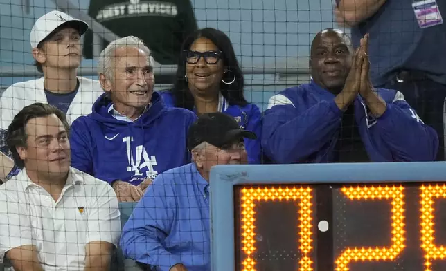 Sandy Koufax, middle left, Cookie Johnson, middle, and Magic Johnson, right, watch Game 1 of baseball's NL Division Series between the Los Angeles Dodgers and the San Diego Padres, Saturday, Oct. 5, 2024, in Los Angeles. (AP Photo/Mark J. Terrill)