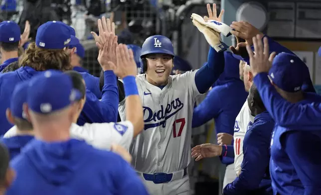 Los Angeles Dodgers' Shohei Ohtani (17) celebrates in the dugout after scoring on a single by Teoscar Hernández during the fourth inning in Game 1 of baseball's NL Division Series against the San Diego Padres, Saturday, Oct. 5, 2024, in Los Angeles. (AP Photo/Ashley Landis)