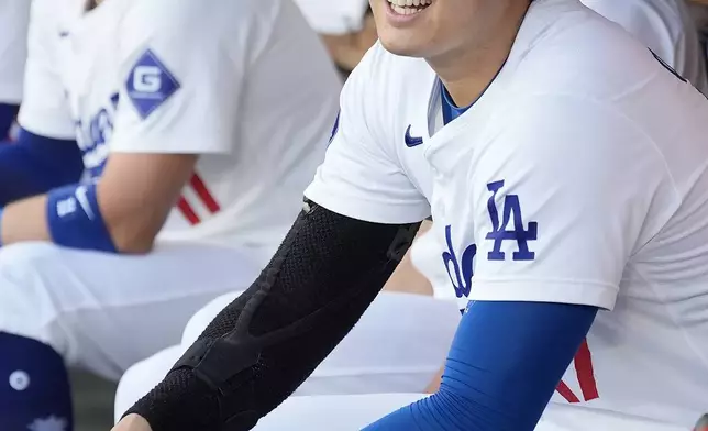 Los Angeles Dodgers' Shohei Ohtani, right, waits for the start of Game 1 of baseball's NL Division Series against the San Diego Padres, Saturday, Oct. 5, 2024, in Los Angeles. (AP Photo/Ashley Landis)