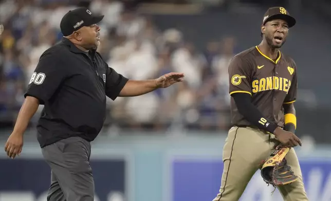 San Diego Padres left fielder Jurickson Profar, right, talks to umpire Adrian Johnson after items were thrown at Profar in the outfield during the seventh inning in Game 2 of a baseball NL Division Series against the Los Angeles Dodgers, Sunday, Oct. 6, 2024, in Los Angeles. (AP Photo/Ashley Landis)