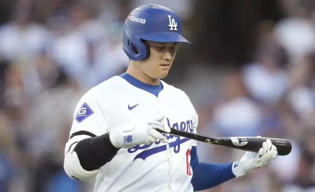 Los Angeles Dodgers' Shohei Ohtani walks back to replace his bat after breaking it on a foul ball during the third inning in Game 2 of a baseball NL Division Series against the San Diego Padres, Sunday, Oct. 6, 2024, in Los Angeles. (AP Photo/Ashley Landis)