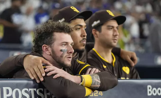 San Diego Padres center fielder Jackson Merrill, left, looks on alongside relief pitcher Jeremiah Estrada, center, and catcher Kyle Higashioka after a loss to the Los Angeles Dodgers in Game 5 of a baseball NL Division Series Friday, Oct. 11, 2024, in Los Angeles. (AP Photo/Mark J. Terrill)