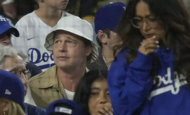 Brad Pitt, in white hat, watches from the stands during Game 1 of baseball's NL Division Series between the Los Angeles Dodgers and the San Diego Padres, Saturday, Oct. 5, 2024, in Los Angeles. (AP Photo/Mark J. Terrill)