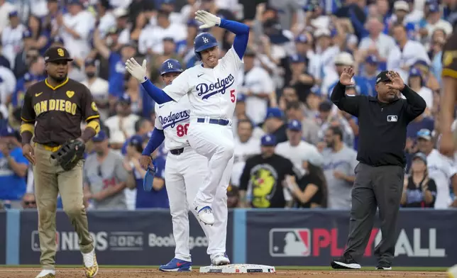 Los Angeles Dodgers' Freddie Freeman (5) reacts after a single as he stands next to San Diego Padres first baseman Luis Arraez during the first inning in Game 5 of a baseball NL Division Series Friday, Oct. 11, 2024, in Los Angeles. (AP Photo/Ashley Landis)