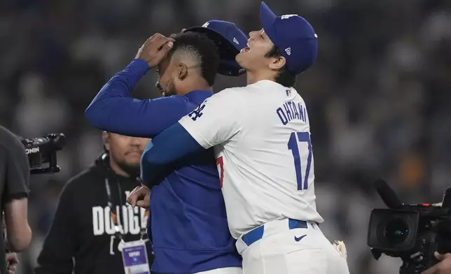 Los Angeles Dodgers' Shohei Ohtani, right, hugs Teoscar Hernández after the Dodgers defeated the San Diego Padres in Game 1 of baseball's NL Division Series, Saturday, Oct. 5, 2024, in Los Angeles. (AP Photo/Ashley Landis)