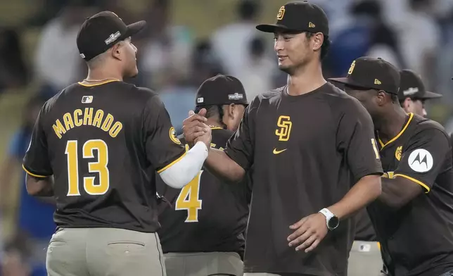 San Diego Padres' Manny Machado, left, shakes hands with pitcher Yu Darvish after a win over the Los Angeles Dodgers in Game 2 of a baseball NL Division Series, Sunday, Oct. 6, 2024, in Los Angeles. (AP Photo/Ashley Landis)