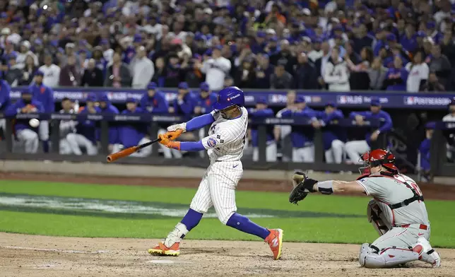 New York Mets' Francisco Lindor (12) connects for a grand slam home run against the Philadelphia Phillies during the sixth inning of Game 4 of the National League baseball playoff series, Wednesday, Oct. 9, 2024, in New York. (AP Photo/Adam Hunger)