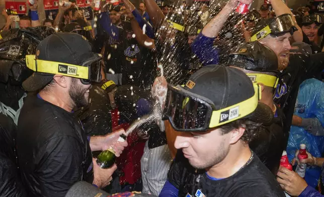 The New York Mets celebrate in the locker room after defeating the Philadelphia Phillies in Game 4 of the National League baseball playoff series, Wednesday, Oct. 9, 2024, in New York. (AP Photo/Frank Franklin II)