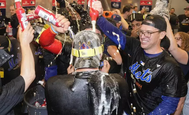 The New York Mets celebrate in the locker room after defeating the Philadelphia Phillies in Game 4 of the National League baseball playoff series, Wednesday, Oct. 9, 2024, in New York. (AP Photo/Frank Franklin II)