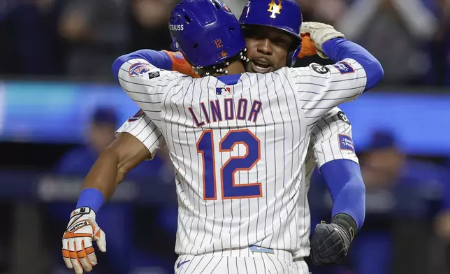 New York Mets' Francisco Lindor (12) hugs Starling Marte (6) after hitting a grand slam home run against the Philadelphia Phillies during the sixth inning of Game 4 of the National League baseball playoff series, Wednesday, Oct. 9, 2024, in New York. (AP Photo/Adam Hunger)