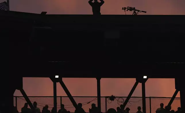 A New York Police Emergency Services Unit officer keeps watch atop Citi Field during Game 3 of the National League baseball playoff series between the New York Mets and the Philadelphia Phillies, Tuesday, Oct. 8, 2024, in New York. (AP Photo/Frank Franklin II)