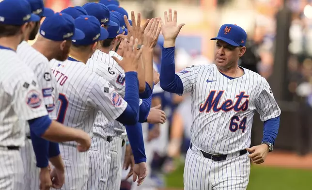 New York Mets manager Carlos Mendoza (64) greets players before Game 3 of the National League baseball playoff series against the Philadelphia Phillies, Tuesday, Oct. 8, 2024, in New York. (AP Photo/Frank Franklin II)