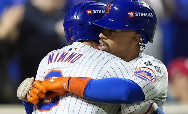 New York Mets Brandon Nimmo (9) hugs Francisco Lindor (12) after Lindor hit a grand slam home run against the Philadelphia Phillies during the sixth inning of Game 4 of the National League baseball playoff series, Wednesday, Oct. 9, 2024, in New York. (AP Photo/Frank Franklin II)