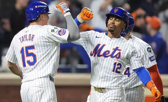 New York Mets' Francisco Lindor (12) is congratulated by Tyrone Taylor (15) after hitting a grand slam home run against the Philadelphia Phillies during the sixth inning of Game 4 of the National League baseball playoff series, Wednesday, Oct. 9, 2024, in New York. (AP Photo/Frank Franklin II)