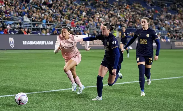 Angel City FC forward Christen Press vies for the ball against Seattle Reign defender Phoebe McClernon, center, and defender Shae Holmes, right, during the second half of an NWSL soccer match Friday, Oct. 4, 2024, in Seattle. Angel City won 1-0. (AP Photo/Lindsey Wasson)